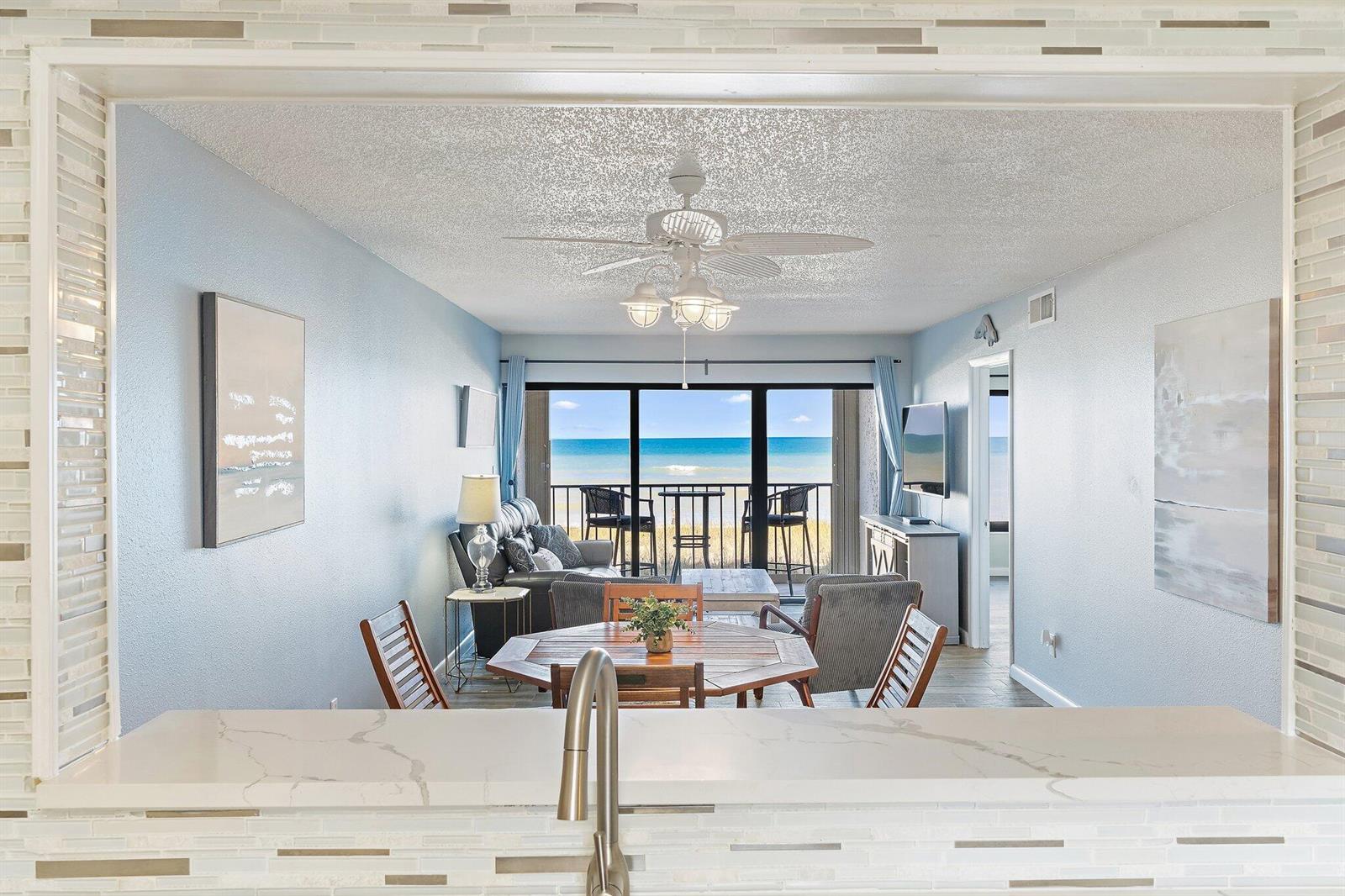 A kitchen counter overlooks a living and dining area with a view of the ocean — 10310 S Ocean Drive # 205, Jensen Beach FL 34957, JENSEN BEACH, FL