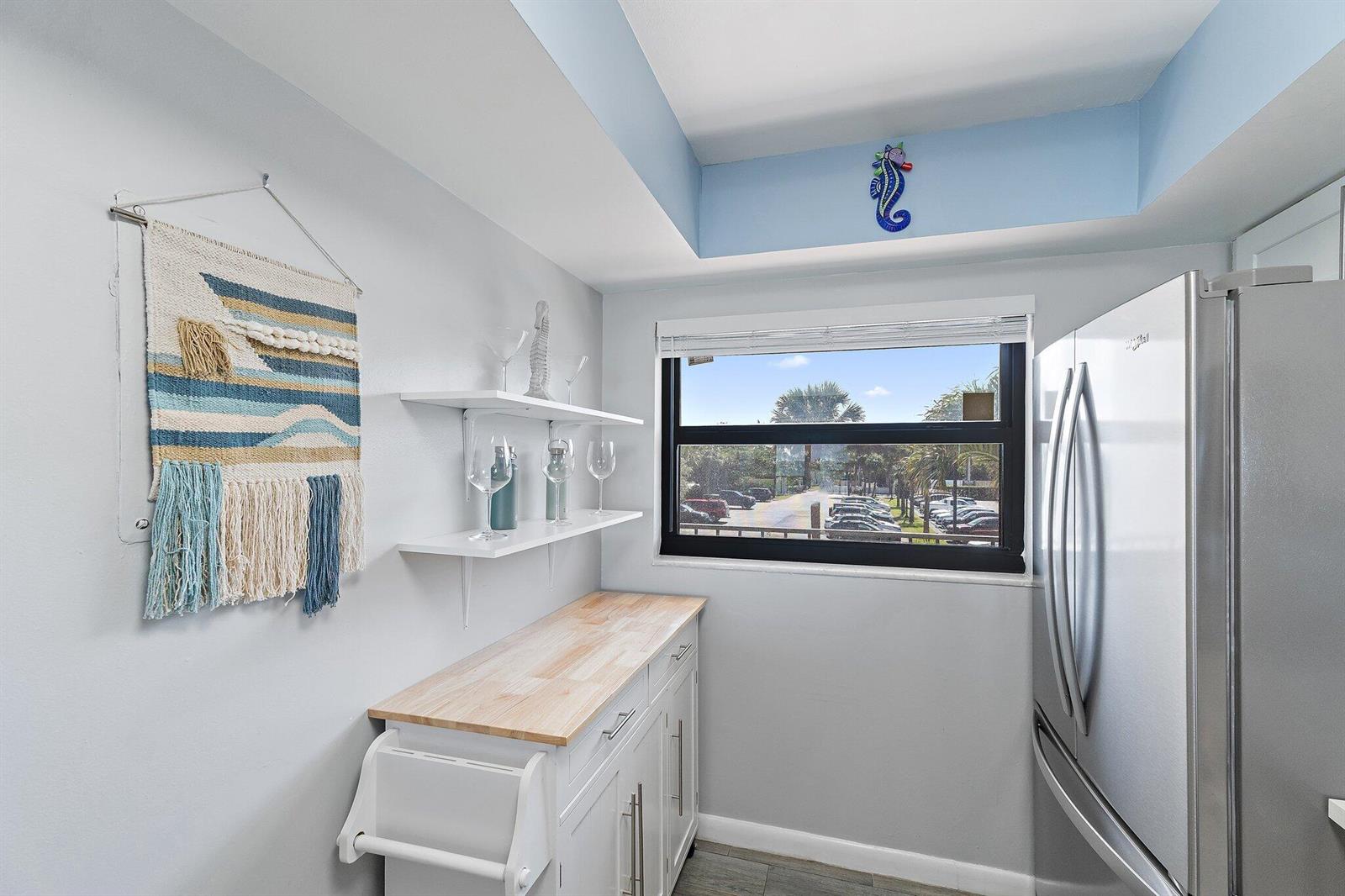 A kitchen nook features white cabinets, a wood countertop, floating shelves, and a window view — 10310 S Ocean Drive # 205, Jensen Beach FL 34957, JENSEN BEACH, FL