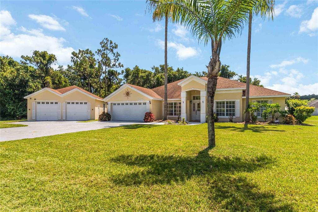A single-story house with a three-car garage, a palm tree, and a grassy front yard — 3225 CANOE CREEK ROAD, ST CLOUD, FL