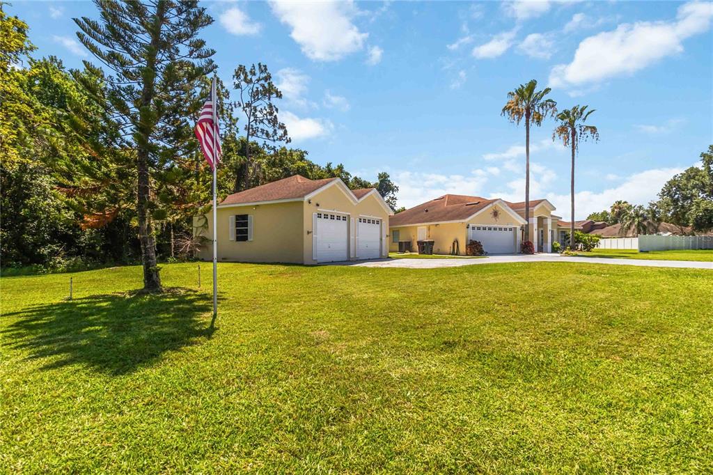 A detached two-car garage sits on a grassy lawn next to a single-story house — 3225 CANOE CREEK ROAD, ST CLOUD, FL