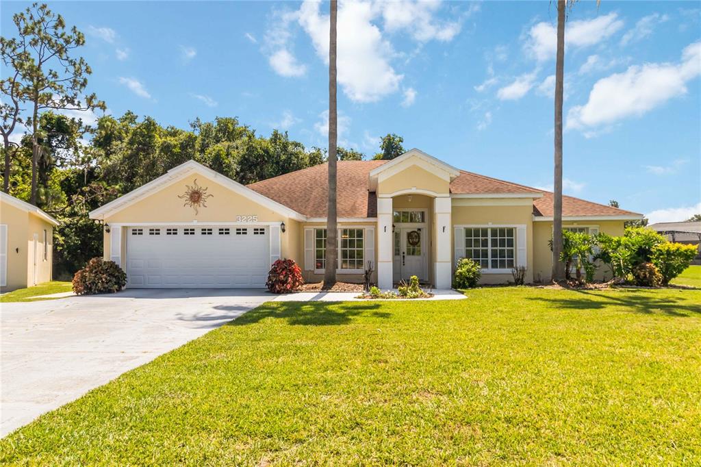 A single-story yellow house with a two-car garage and palm trees in the front yard — 3225 CANOE CREEK ROAD, ST CLOUD, FL