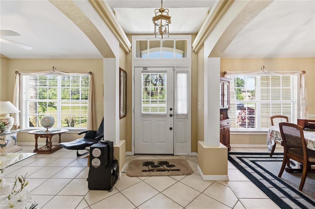 An entryway with tile floors, a white front door, and arched openings to adjacent rooms — 3225 CANOE CREEK ROAD, ST CLOUD, FL
