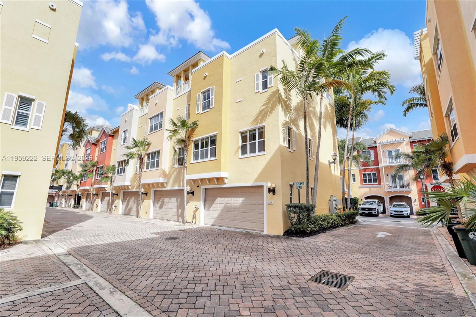A row of multi-story yellow townhomes with attached garages and brick-paved driveways — 2318 Vintage Dr # 2318, Lighthouse Point FL 33064, LIGHTHOUSE POINT, FL