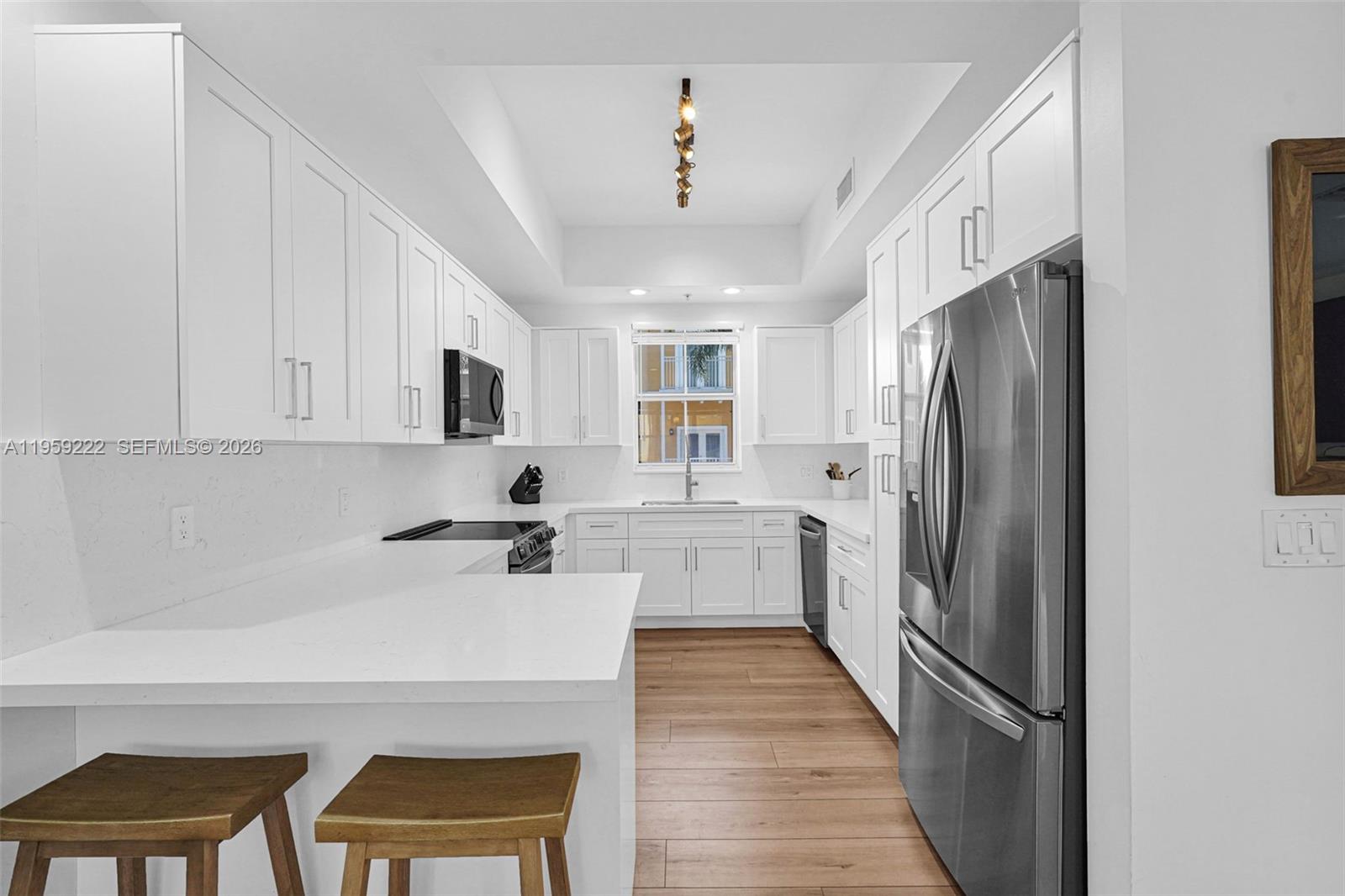 A modern kitchen features white cabinetry, stainless steel appliances, and light wood-look flooring — 2318 Vintage Dr # 2318, Lighthouse Point FL 33064, LIGHTHOUSE POINT, FL