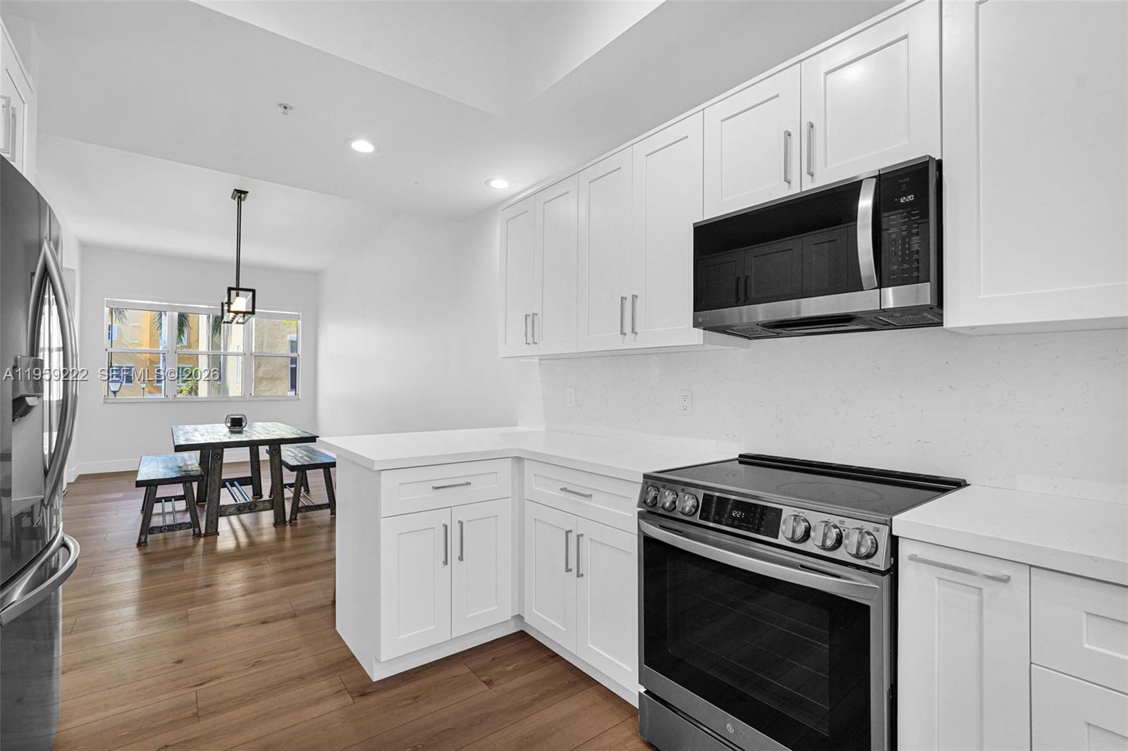 A modern kitchen features white cabinets, stainless steel appliances, and an adjacent dining area — 2318 Vintage Dr # 2318, Lighthouse Point FL 33064, LIGHTHOUSE POINT, FL