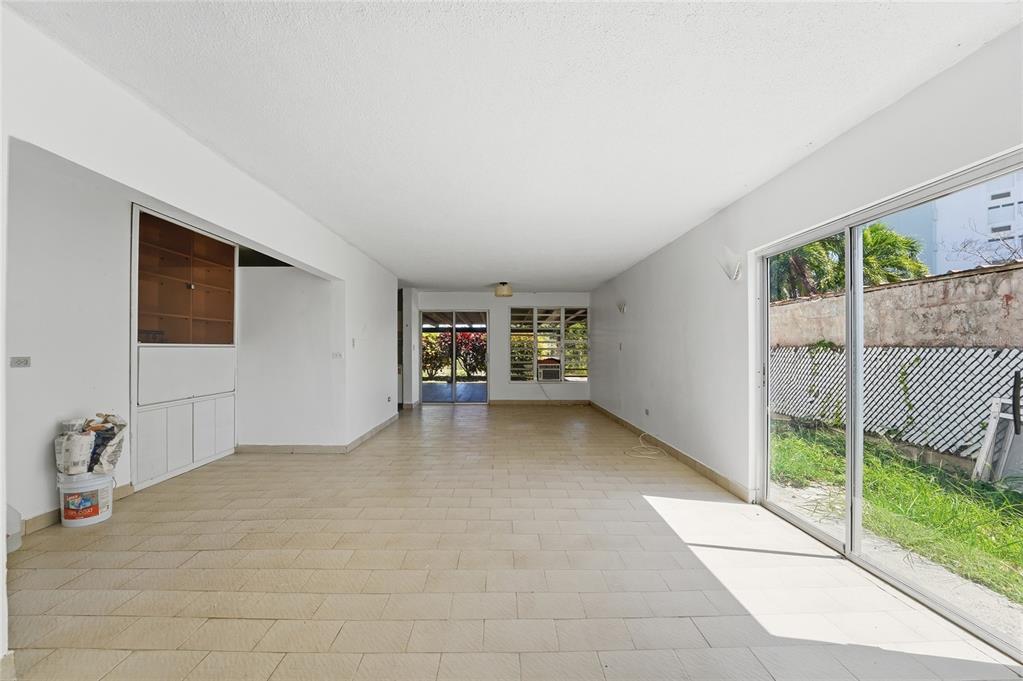 An empty living room features white walls, light-colored tile flooring, and large sliding glass doors — Playa Santa CALLE 3 UNIT D-13, ENSENADA, PR