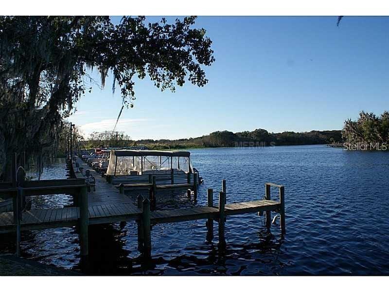 A wooden boat dock extends into a calm lake under a clear blue sky — 205 SHER LANE, DEBARY, FL