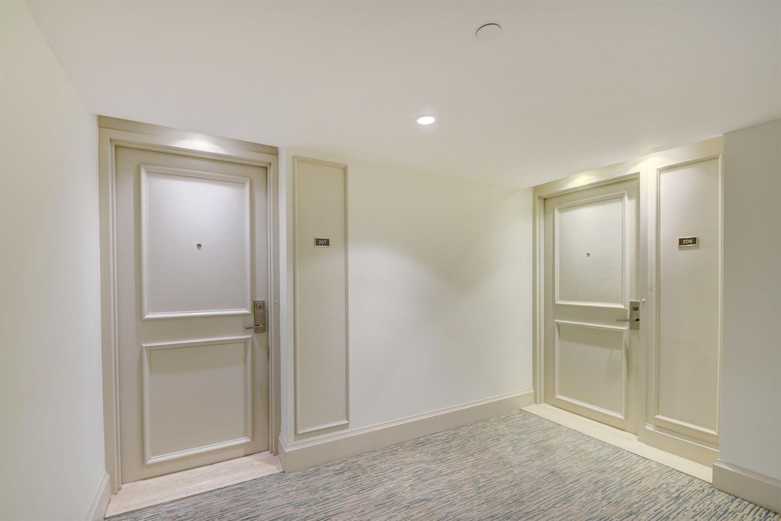A hotel hallway features two light-colored doors numbered 207 and 206 with patterned carpeting — 3250 S Ocean Boulevard # 207s, Palm Beach FL 33480, PALM BEACH, FL