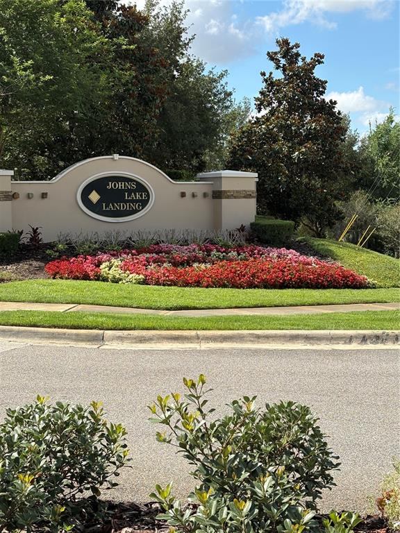 A neighborhood entrance sign for Johns Lake Landing sits behind a bed of colorful flowers — 17042 CRESTMONT BOULEVARD, CLERMONT, FL