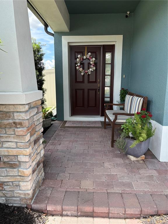 A front porch features a dark red door, a wooden bench, and a potted plant — 17042 CRESTMONT BOULEVARD, CLERMONT, FL