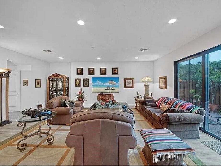 A spacious living room features leather furniture, a large television, and sliding glass patio doors — 3199 Santa Catalina Place, FL 33467, FL