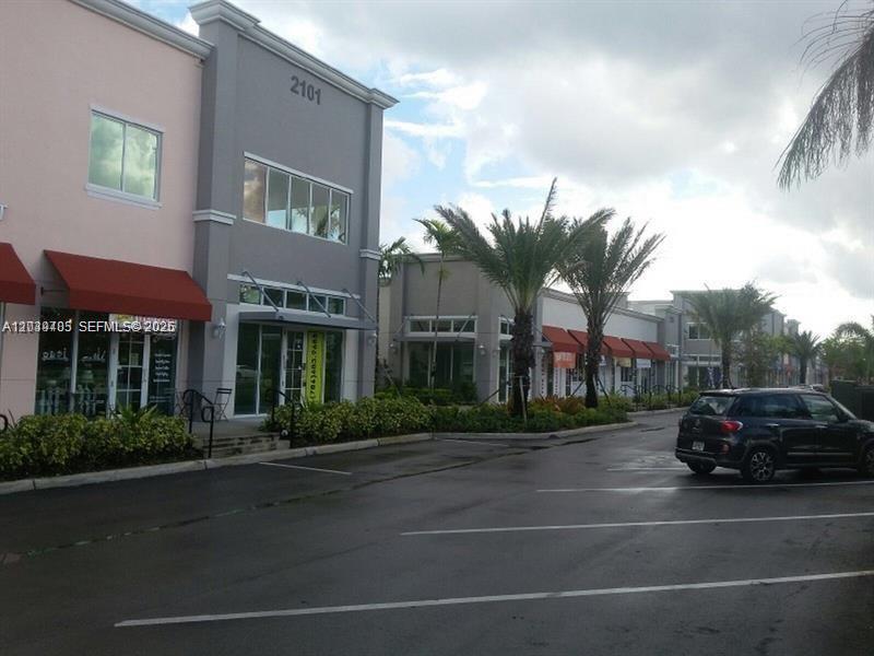 A view of a commercial building exterior with a parking lot and palm trees — 2101 SW 101st Ave # 204, Miramar FL 33025, MIRAMAR, FL