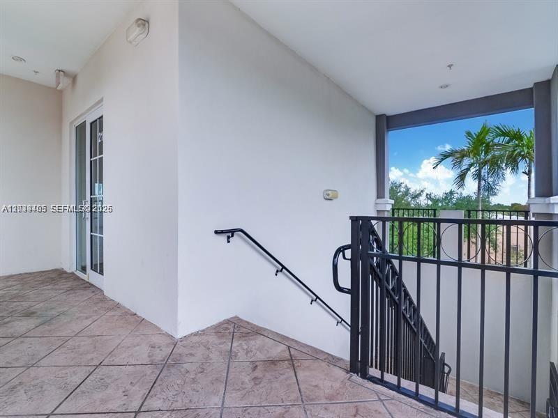 A tiled balcony features a black metal staircase railing and a glass door entrance — 2101 SW 101st Ave # 204, Miramar FL 33025, MIRAMAR, FL