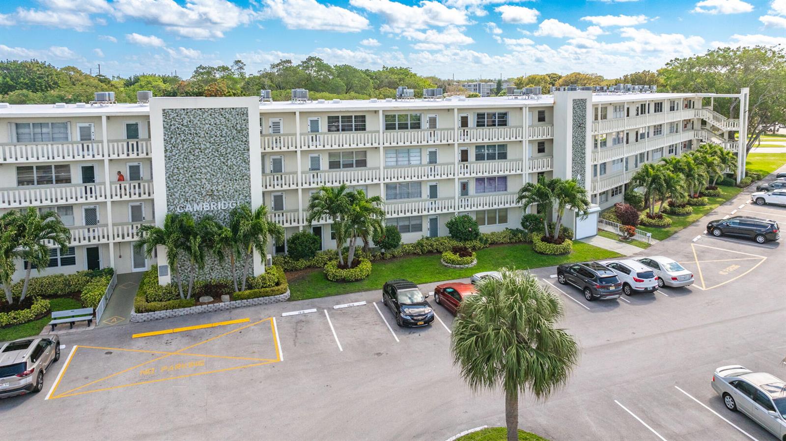 An exterior view of a multi-story apartment building with a parking lot in front — 4002 Cambridge A # 4002, Deerfield Beach FL 33442, DEERFIELD BEACH, FL