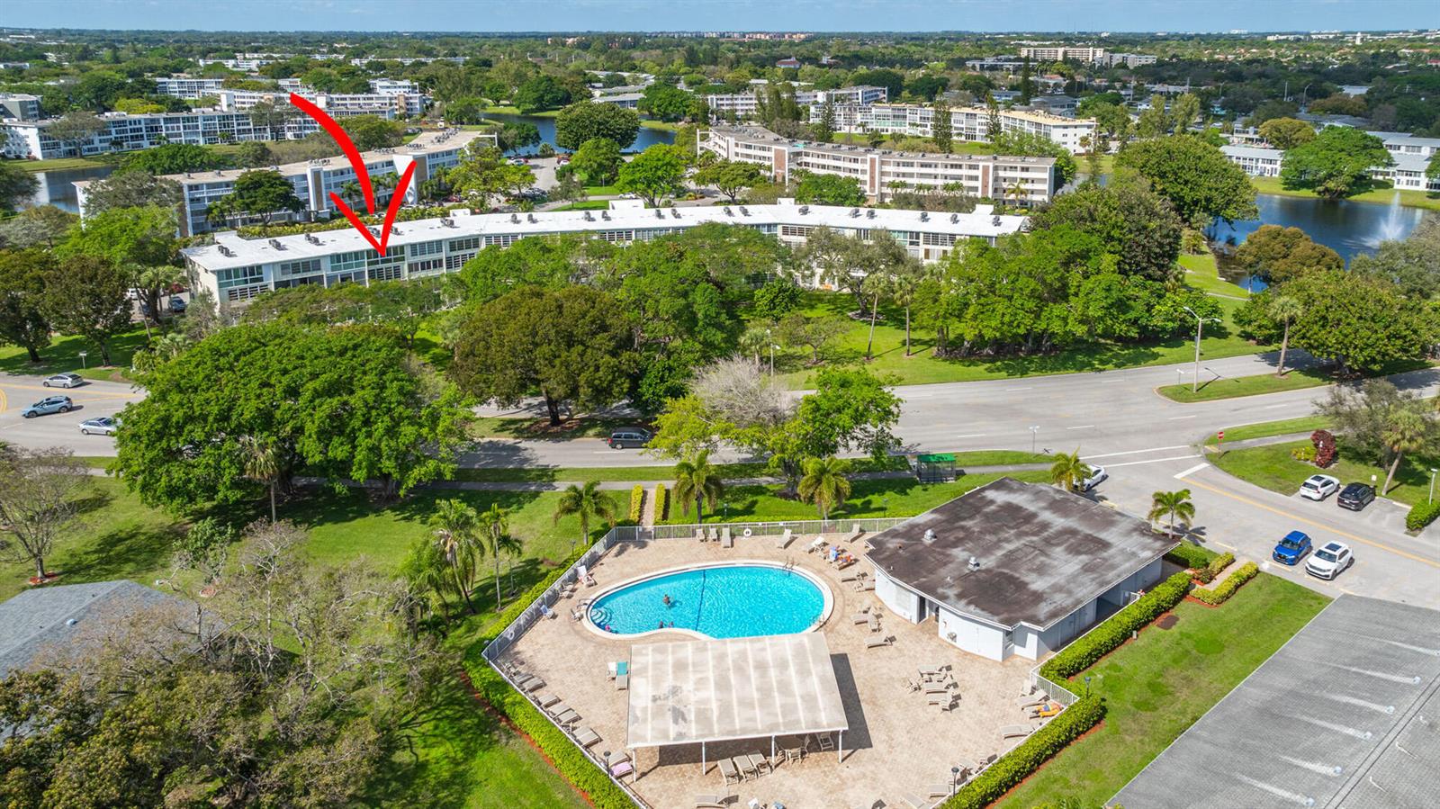 An aerial view shows a multi-story apartment building with a pool and clubhouse in front — 4002 Cambridge A # 4002, Deerfield Beach FL 33442, DEERFIELD BEACH, FL