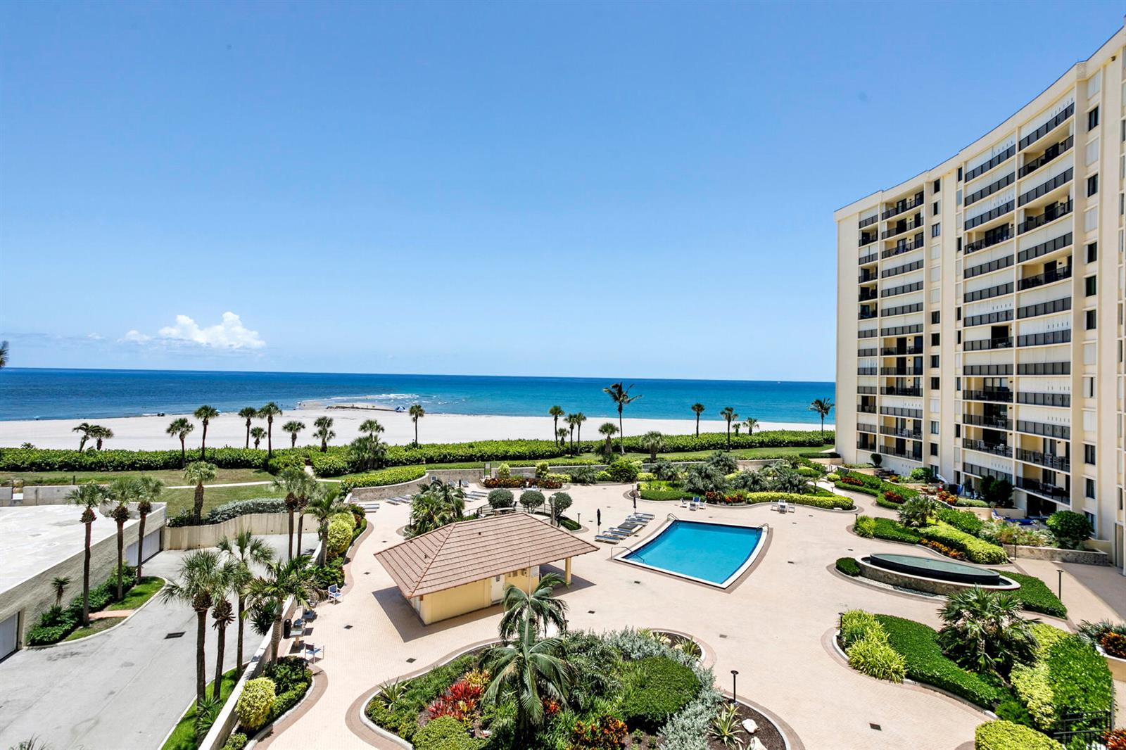 An aerial view of a beachfront apartment complex with a swimming pool and landscaped courtyard — 300 Ocean Trail Way # 510, Jupiter FL 33477, JUPITER, FL