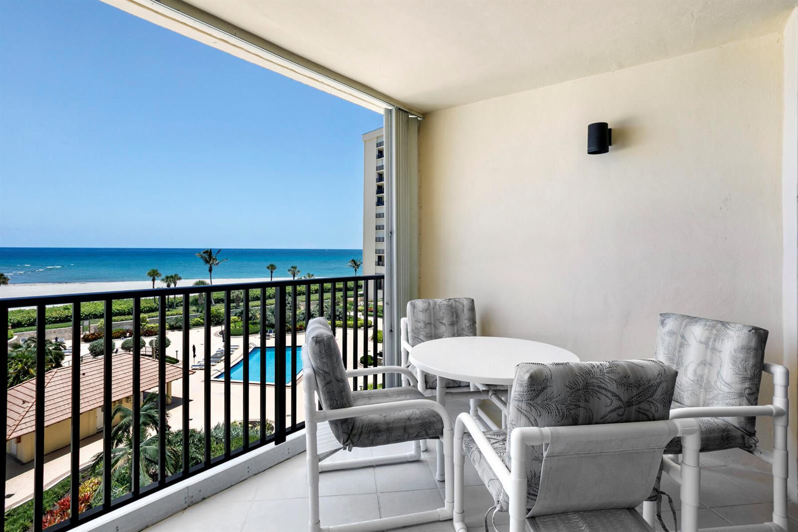 A balcony with patio furniture overlooks a swimming pool, beach, and the ocean — 300 Ocean Trail Way # 510, Jupiter FL 33477, JUPITER, FL