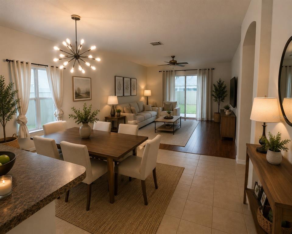 An open-concept living and dining area features tile floors, a wooden dining table, and neutral furniture — 10117 CELTIC ASH DRIVE, RUSKIN, FL