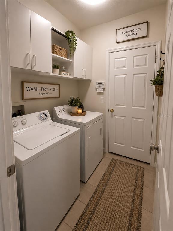 A laundry room features white cabinets, a washer and dryer, and a neutral tile floor — 10117 CELTIC ASH DRIVE, RUSKIN, FL
