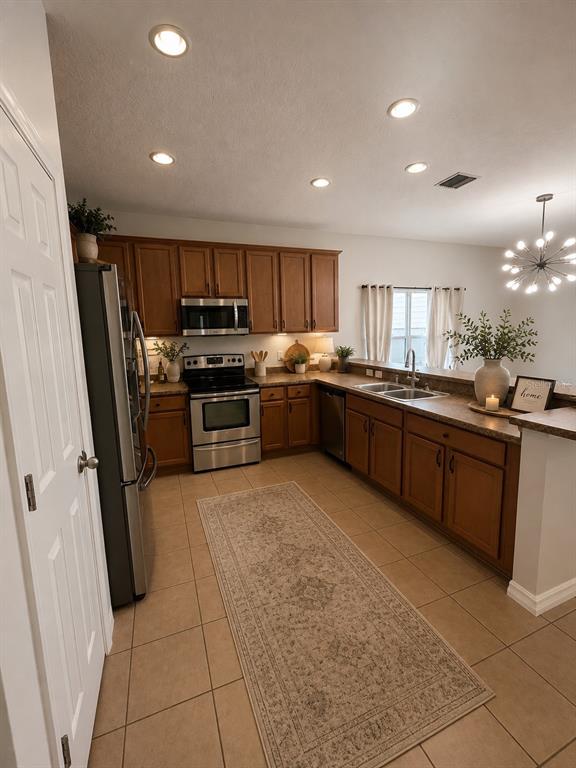 A kitchen features wood cabinets, stainless steel appliances, tile flooring, and a long runner rug — 10117 CELTIC ASH DRIVE, RUSKIN, FL