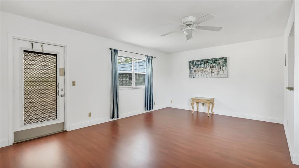 A living room with white walls, wood-look flooring, a ceiling fan, and a glass-paneled door — 703 Brittany # O, Delray Beach FL 33446, DELRAY BEACH, FL
