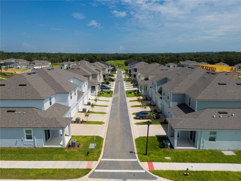 An aerial view shows a suburban street lined with modern townhouses and driveways — 104 ROYAL RANCH ROAD, GROVELAND, FL