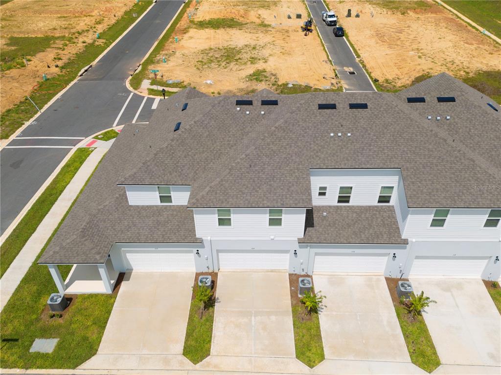 An aerial view shows a row of modern townhouses with attached garages and concrete driveways — 104 ROYAL RANCH ROAD, GROVELAND, FL