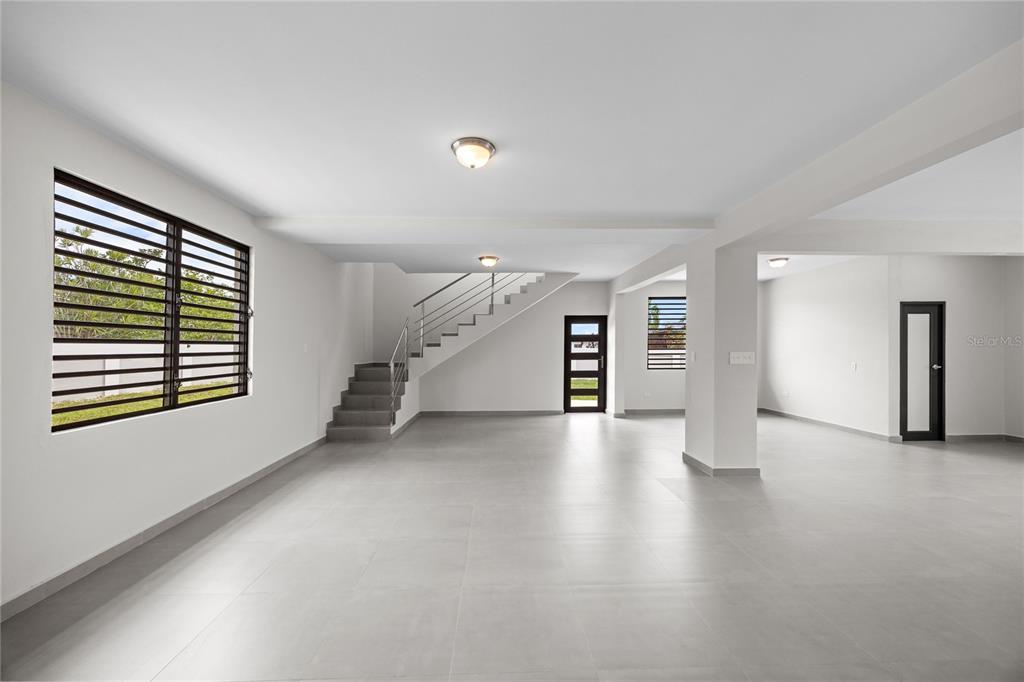 A spacious, minimalist room features light gray tile floors, white walls, and a staircase — 4 REXVILLE VAN SCOY, BAYAMON, PR