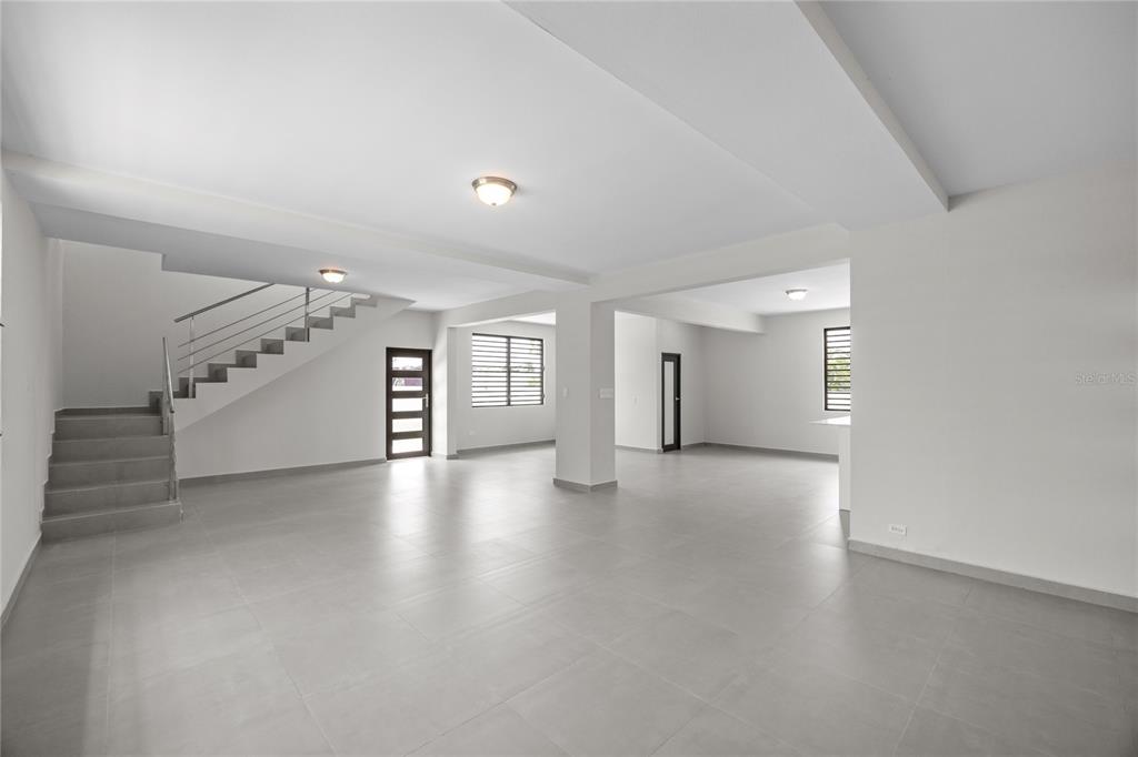 An open-concept living area features gray tile flooring, white walls, and a modern staircase — 4 REXVILLE VAN SCOY, BAYAMON, PR