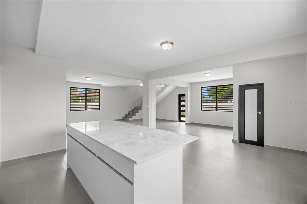 A modern, open-concept kitchen and living area features a white marble island and tiled floors — 4 REXVILLE VAN SCOY, BAYAMON, PR