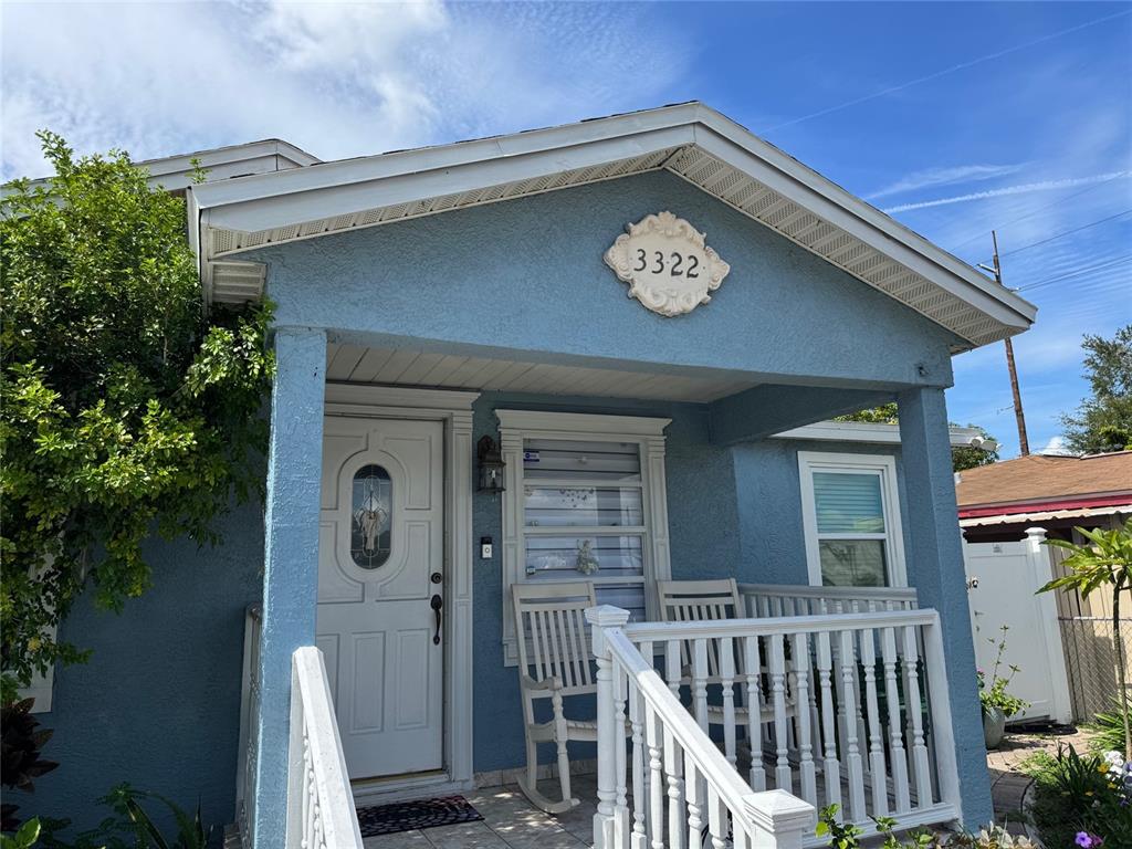 A blue house exterior features a front porch with white railings and a rocking chair — 3322 W SAINT JOSEPH STREET, TAMPA, FL