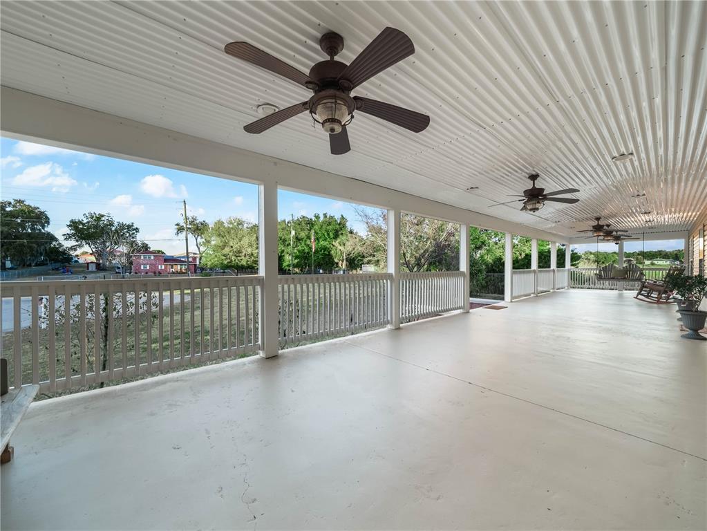 A long, covered porch features a concrete floor, white railings, and multiple ceiling fans — 124 PANGOLA DRIVE, WINTER HAVEN, FL