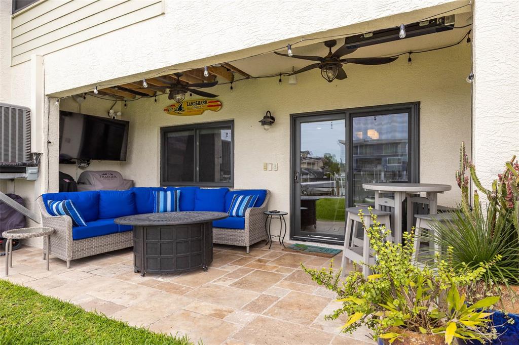 A covered patio features stone flooring, a blue sectional sofa, and a fire pit table — 2395 HANOVER DR, DUNEDIN, FL