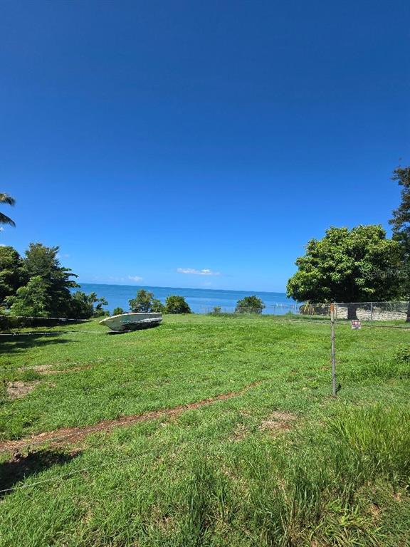 A grassy vacant lot overlooks the ocean with a small boat resting on the land — BO GUANAJIBO CARR 102, CABO ROJO, PR