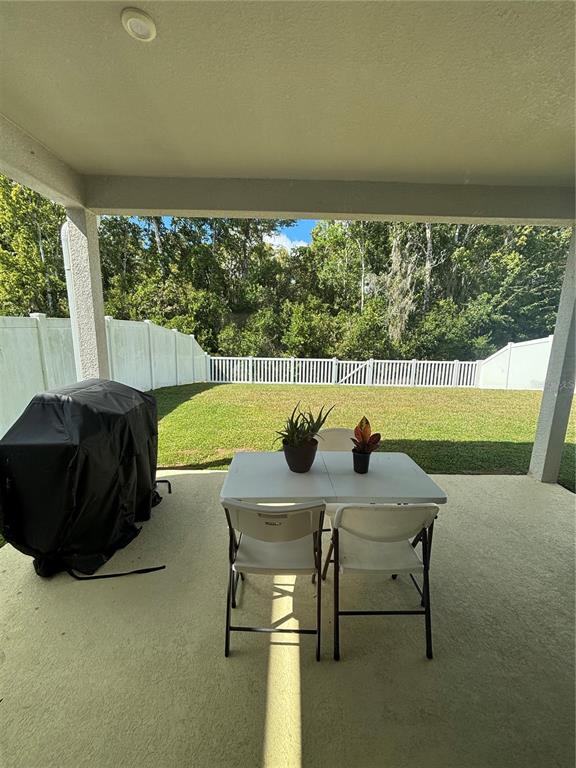 A covered patio features a folding table, two chairs, and a grill under a cover — 11931 THORNCREST DRIVE, SPRING HILL, FL