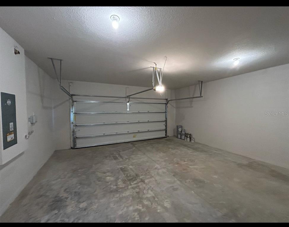 An empty two-car garage with a concrete floor, white walls, and a sectional door — 11931 THORNCREST DRIVE, SPRING HILL, FL