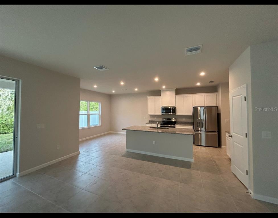 A carpeted staircase leads down to a living room with tile floors and sliding doors — 11931 THORNCREST DRIVE, SPRING HILL, FL