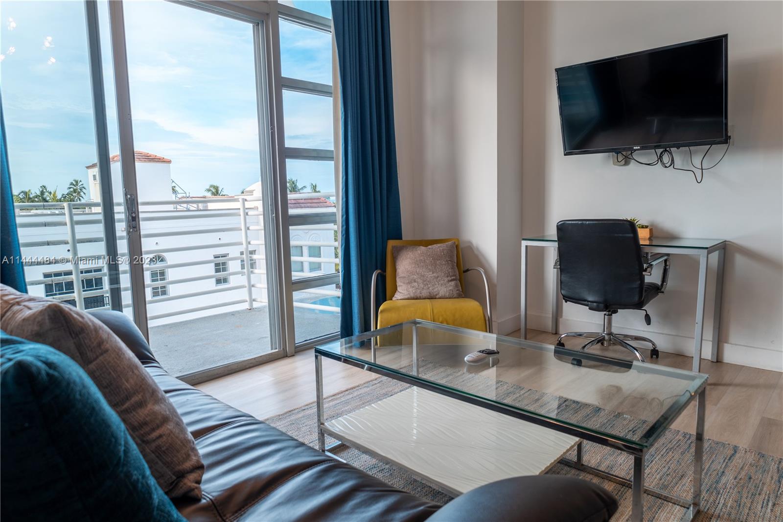 A living room features a glass coffee table, a yellow armchair, and a desk area — 1052 Ocean Dr # C503, Miami Beach FL 33139, MIAMI BEACH, FL