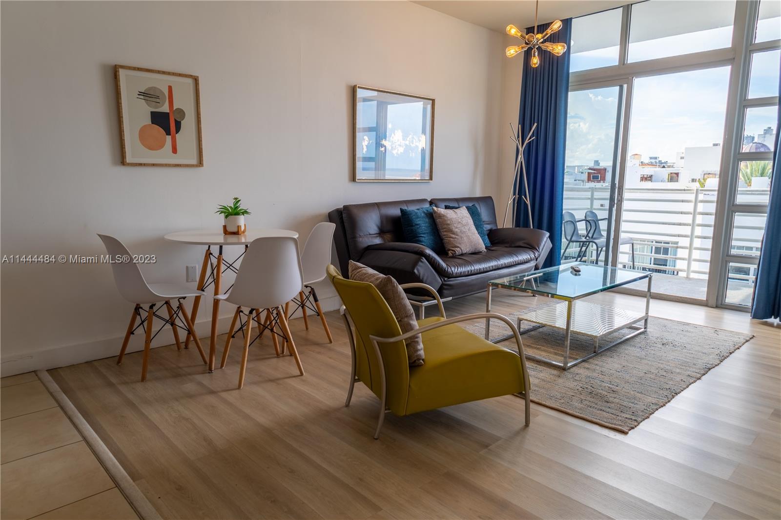 A living room features a dark sofa, a yellow armchair, and a small dining area — 1052 Ocean Dr # C503, Miami Beach FL 33139, MIAMI BEACH, FL