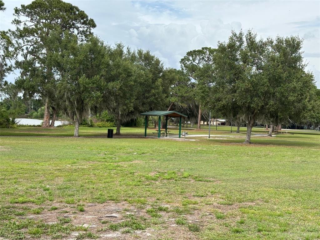 A grassy park area features a small covered picnic pavilion surrounded by mature trees — 3790 AVENUE U NW, WINTER HAVEN, FL