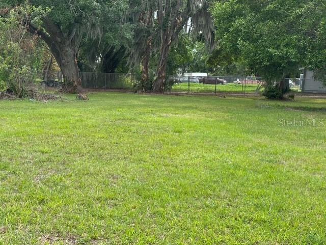 A grassy, vacant lot features several large trees with Spanish moss and a chain-link fence — 3790 AVENUE U NW, WINTER HAVEN, FL