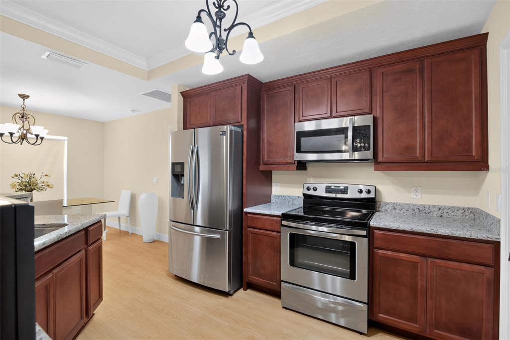 A kitchen with dark wood cabinets, stainless steel appliances, and granite countertops — 24906 NW 202ND LANE, HIGH SPRINGS, FL