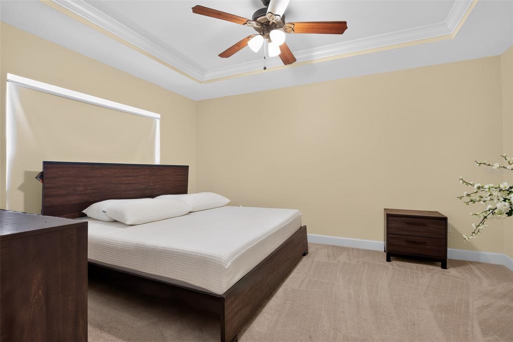 A bedroom with beige walls, a dark wood bed frame, and a ceiling fan — 24906 NW 202ND LANE, HIGH SPRINGS, FL