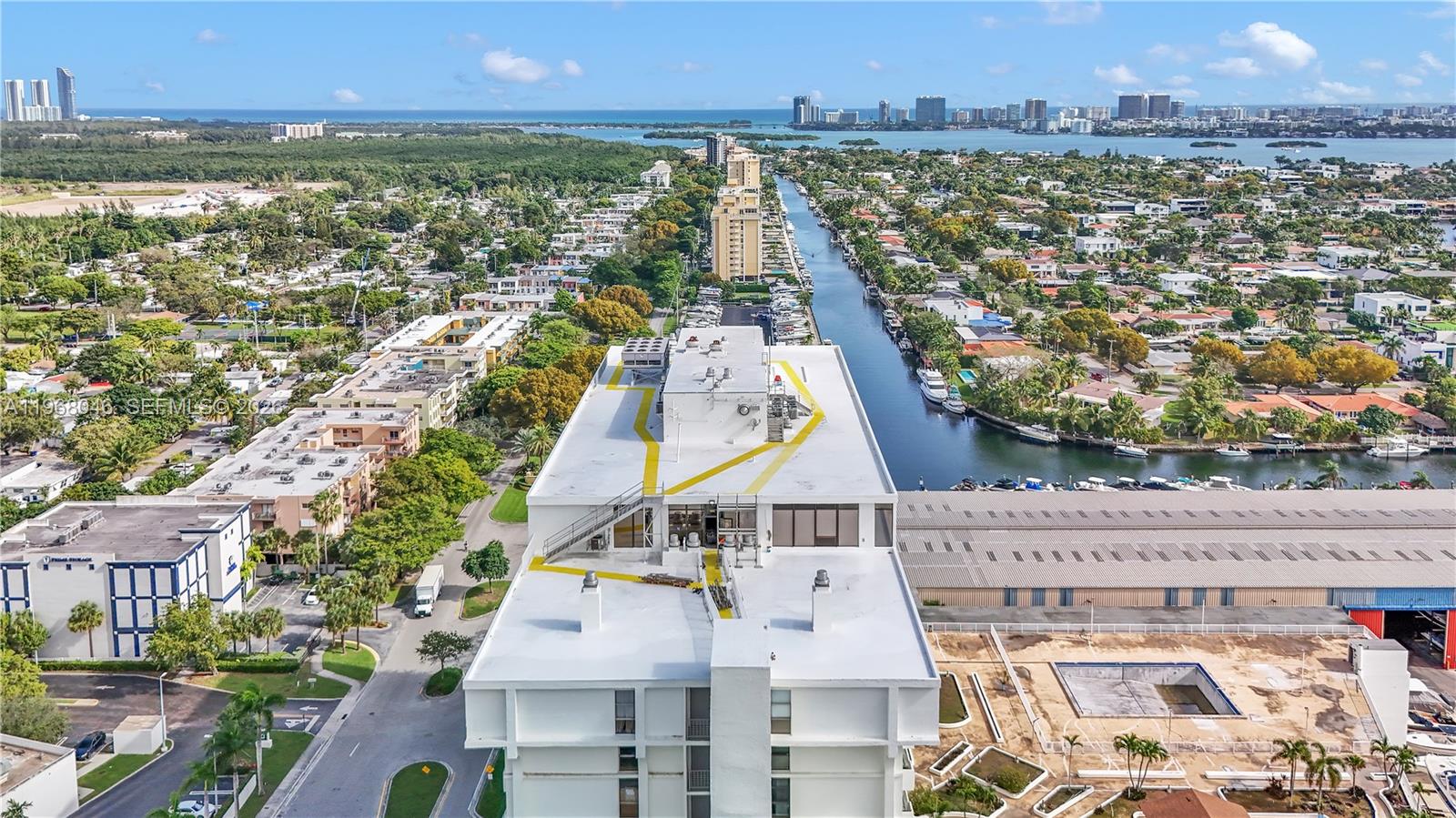 An aerial view shows a white high-rise building rooftop overlooking a canal and neighborhood — 13499 Biscayne Blvd # 3, North Miami FL 33181, NORTH MIAMI, FL