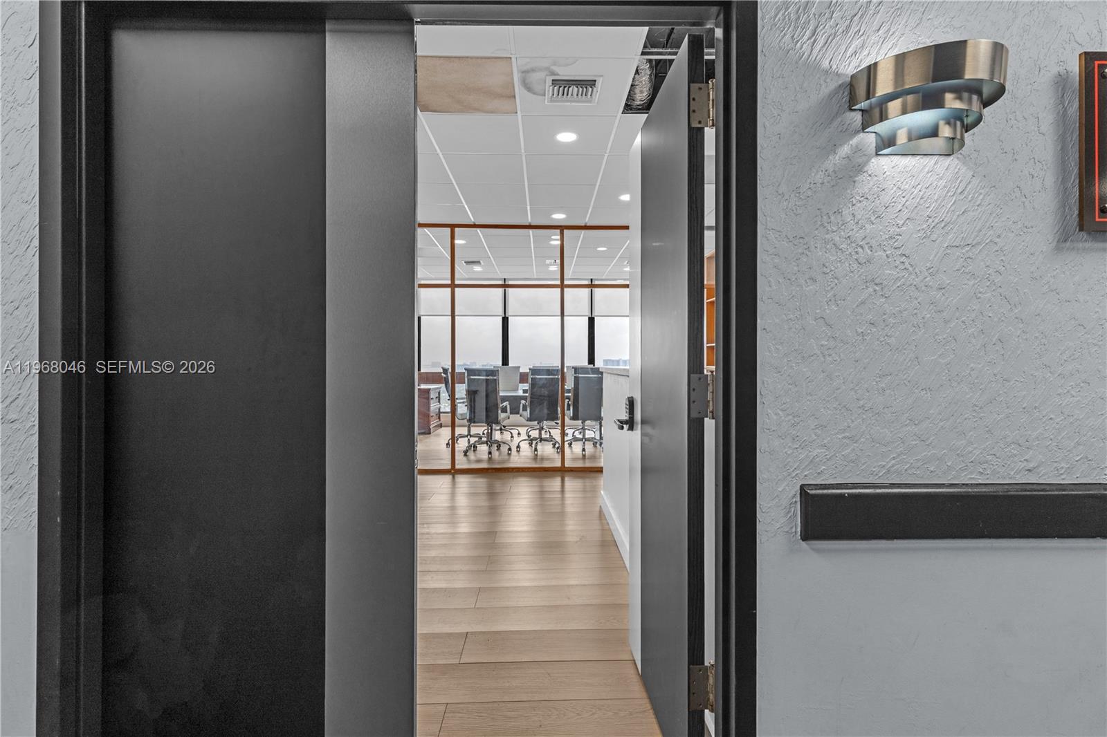 A doorway opens into a modern office space with glass partitions and wood-look flooring — 13499 Biscayne Blvd # 3, North Miami FL 33181, NORTH MIAMI, FL