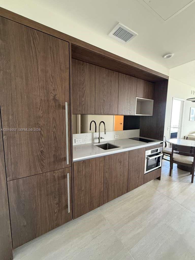 A modern kitchen features dark wood cabinetry, a white countertop, and a stainless steel sink — 1611 SW 2nd ave # 911, Miami FL 33129, MIAMI, FL