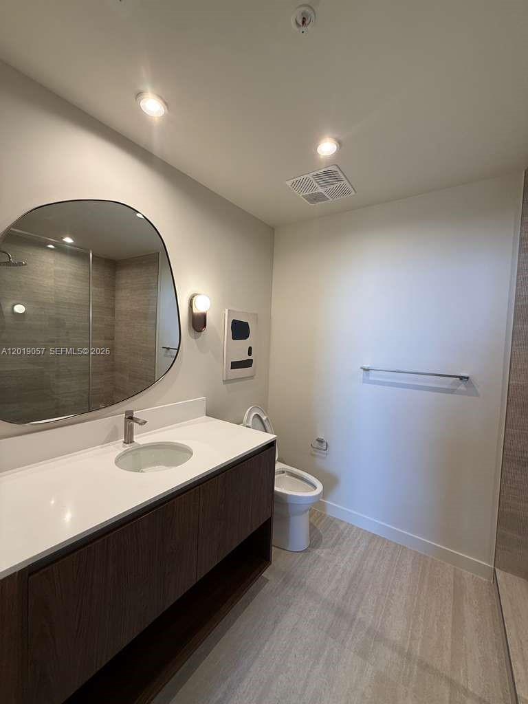 A modern bathroom features a floating vanity, a round mirror, and a walk-in shower — 1611 SW 2nd ave # 911, Miami FL 33129, MIAMI, FL