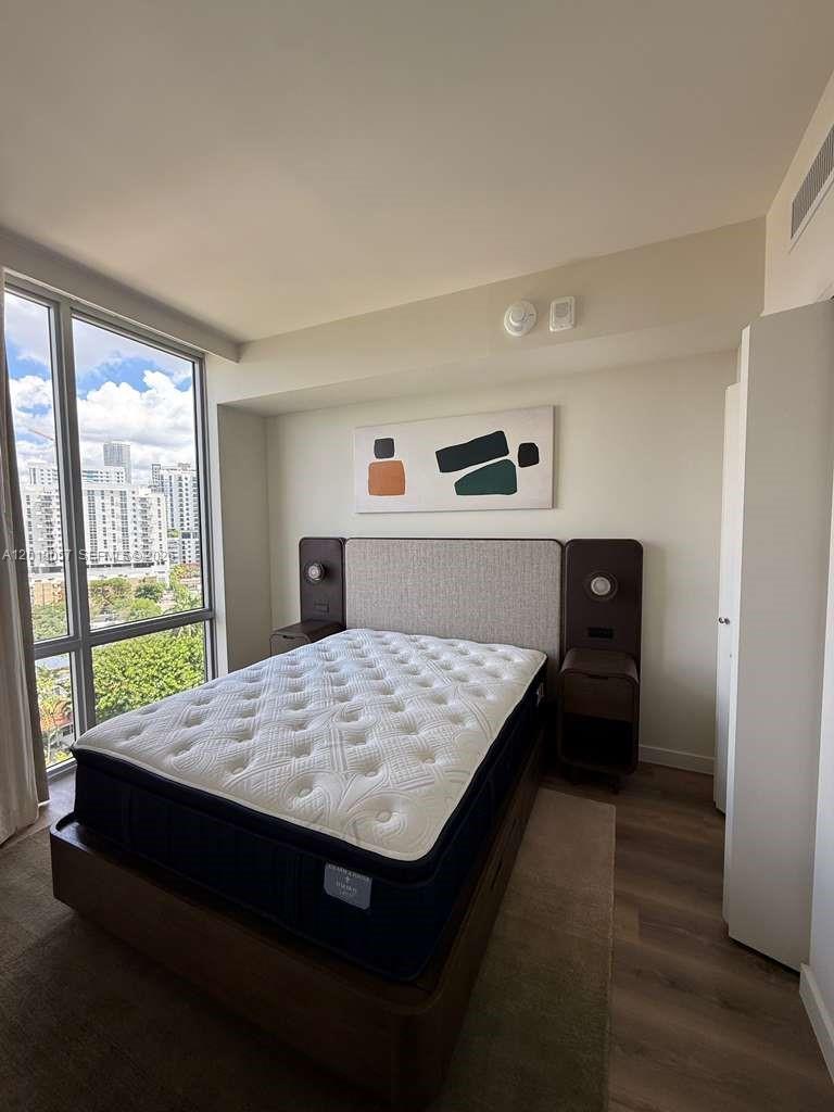 A bedroom features a bed with a headboard, nightstands, and a large window overlooking city buildings — 1611 SW 2nd ave # 911, Miami FL 33129, MIAMI, FL