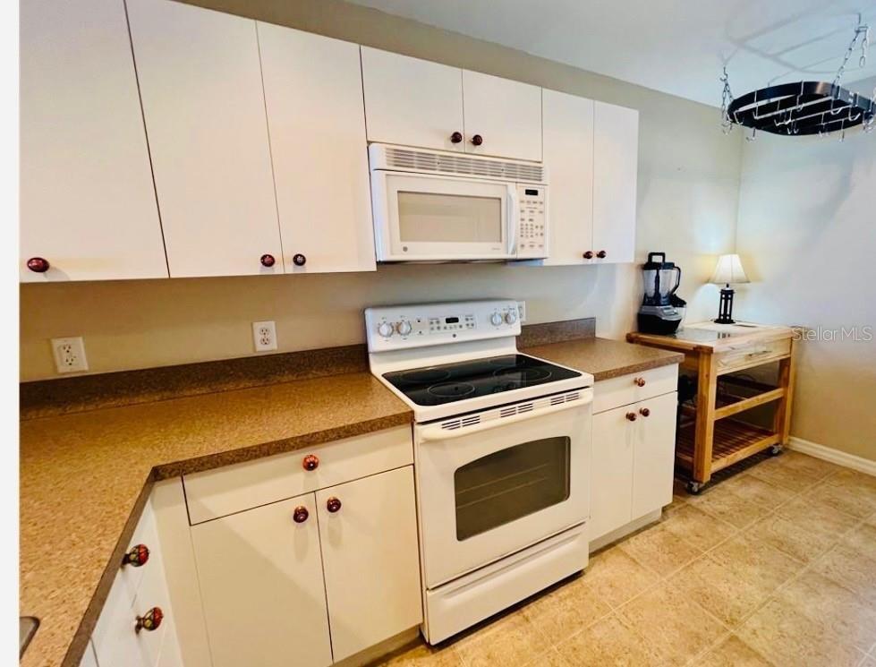 A kitchen features white cabinets, a white electric range, and tan laminate countertops — 1457 SAN CRISTOBAL AVENUE UNIT 3203, PUNTA GORDA, FL