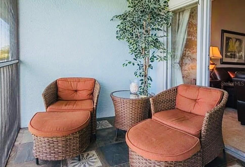 A covered patio features two wicker chairs with matching ottomans and a small glass-topped table — 1457 SAN CRISTOBAL AVENUE UNIT 3203, PUNTA GORDA, FL